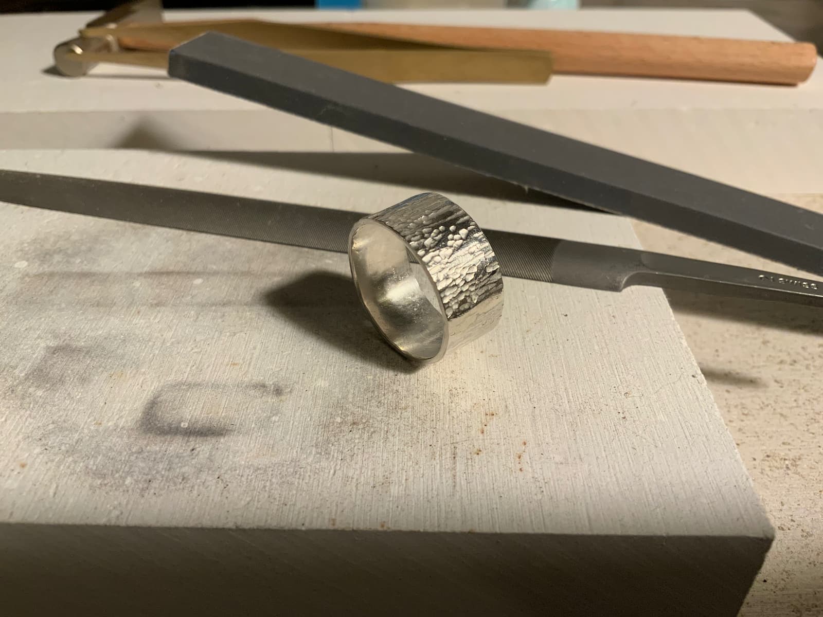 A textured silver band, the first piece off the bench